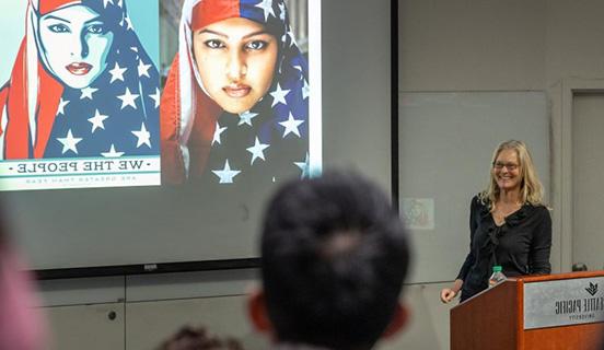 Professor 金伯利•西格尔画 presents on her book Superheroes in the Streets, displaying a photo of a women in a stars-and-stripes hijab