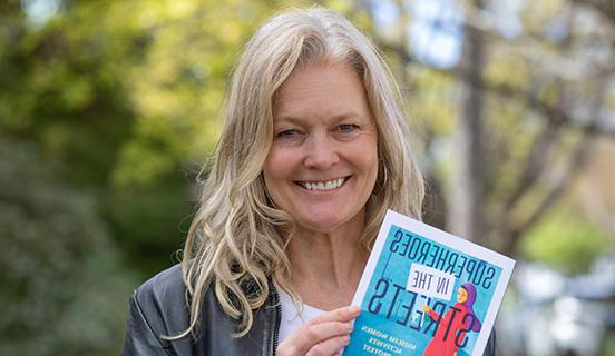 Professor 金伯利·韦德·西格尔 poses with her book Superheroes in the Streets